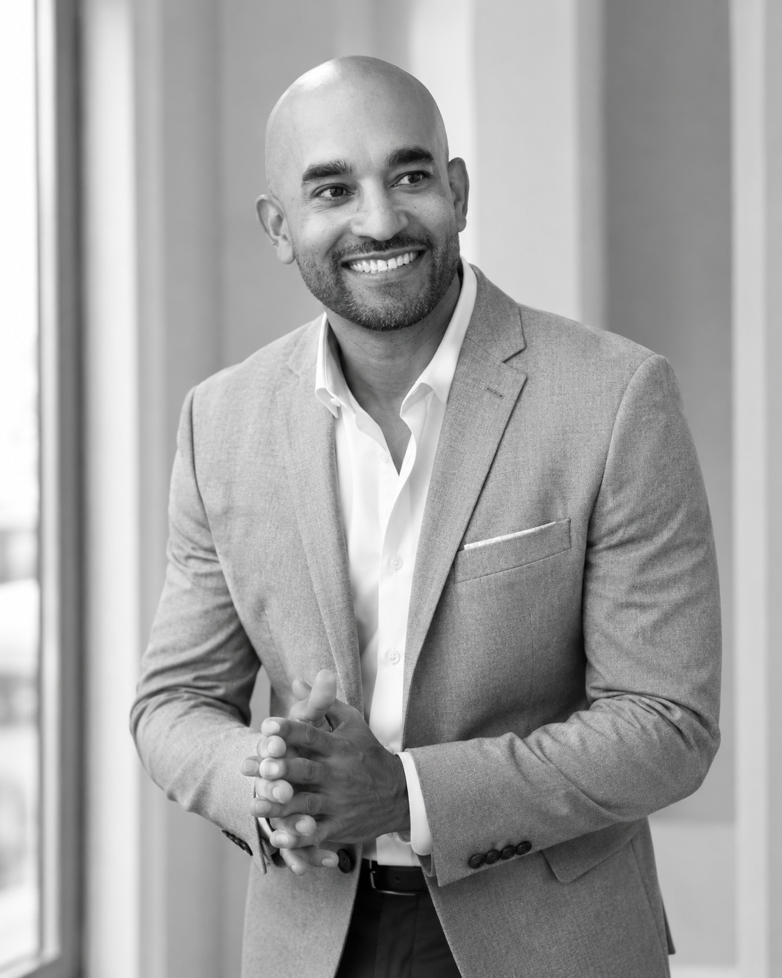 Stephen A. Hart standing in a grey suit with his hands clasped